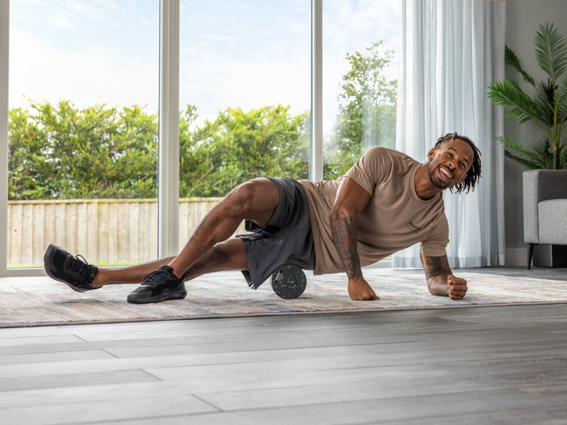 Man rolling his thigh on a Core Balance massage roller.